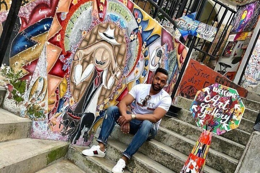 Una persona sentada en unas escaleras con arte callejero y grafitis coloridos en las paredes. 3