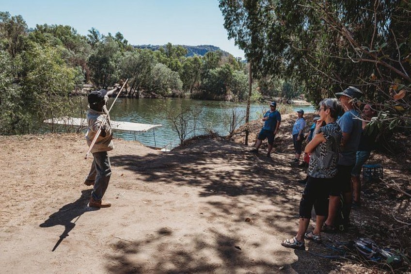 A person fishing by a lake with a group of people watching. 2