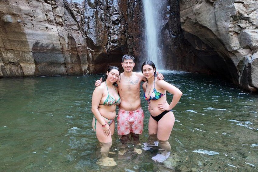 Three people in a natural setting with a waterfall and rocky cliffs. 4