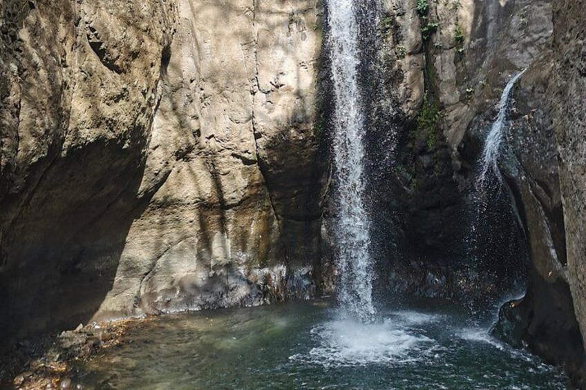 A waterfall cascading into a pool surrounded by rocky cliffs. 3