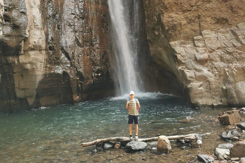 A person standing by a waterfall in a rocky area. 3