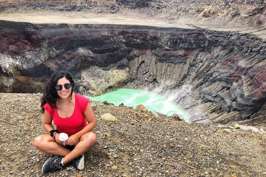 Una persona sentada sobre una superficie rocosa cerca de una masa de agua verdosa, con un acantilado escarpado al fondo. 5