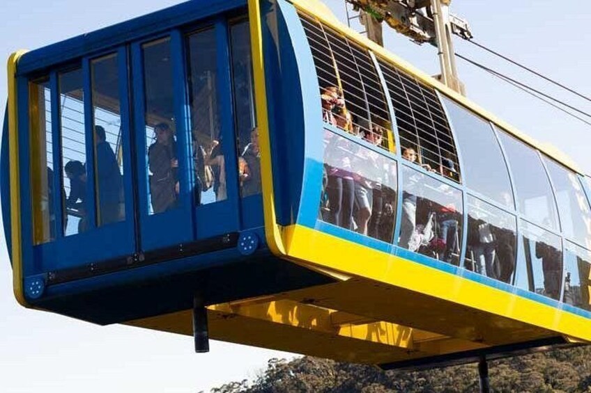 A cable car with passengers, a clear sky, and a mountainous landscape. 5
