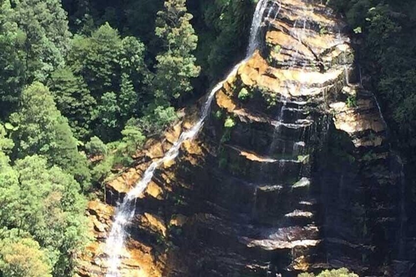 Une cascade se déversant le long d’une falaise rocheuse, entourée d’un feuillage verdoyant et luxuriant. 2