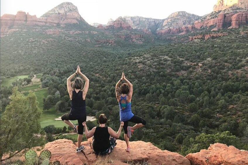 Deux personnes pratiquent le yoga sur un rocher, avec une vue panoramique sur un paysage montagneux. 2