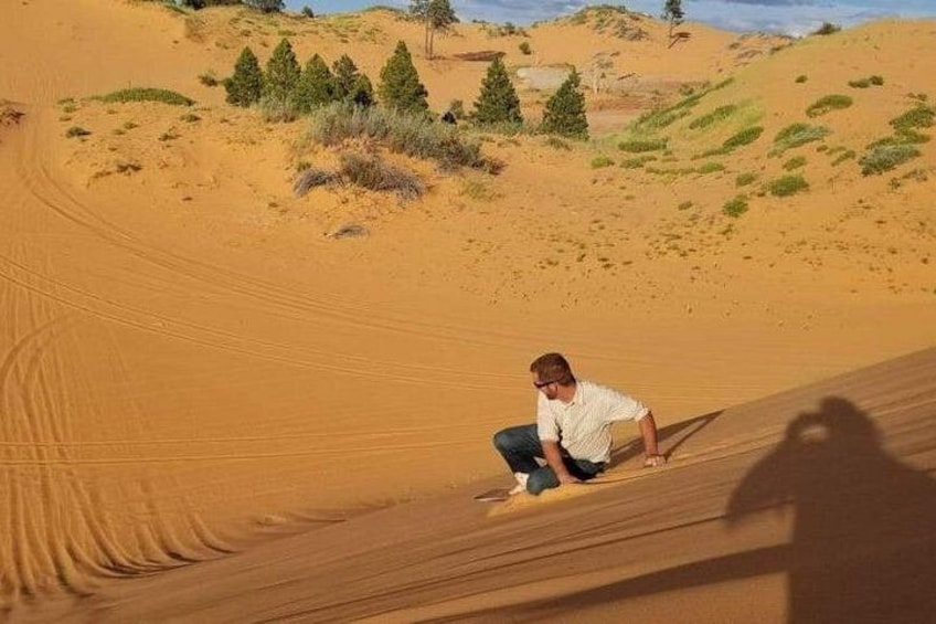 Una persona deslizándose por una duna de arena. 3