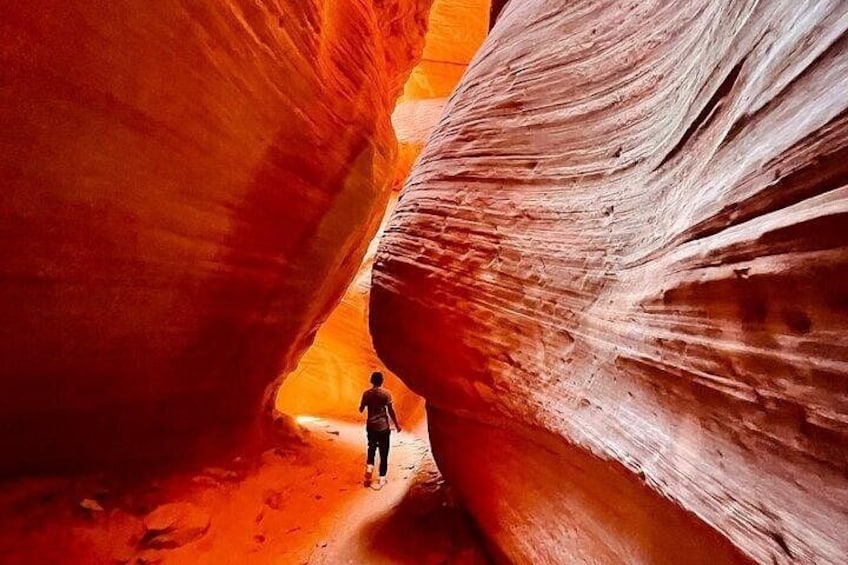 Una persona caminando por un cañón estrecho con paredes de roca roja. 1