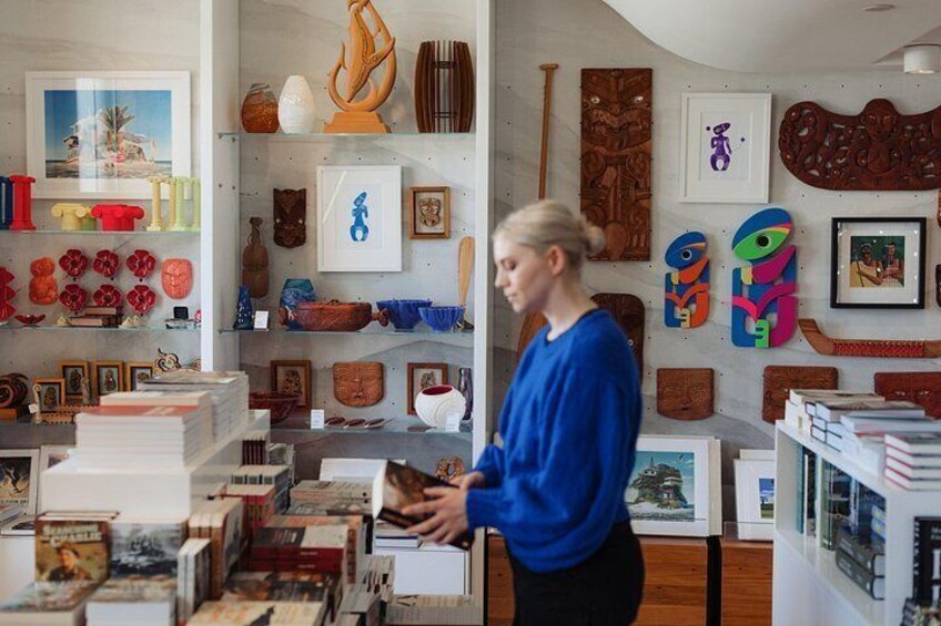 A person in a blue shirt browsing through books and decorative items in a store. 2