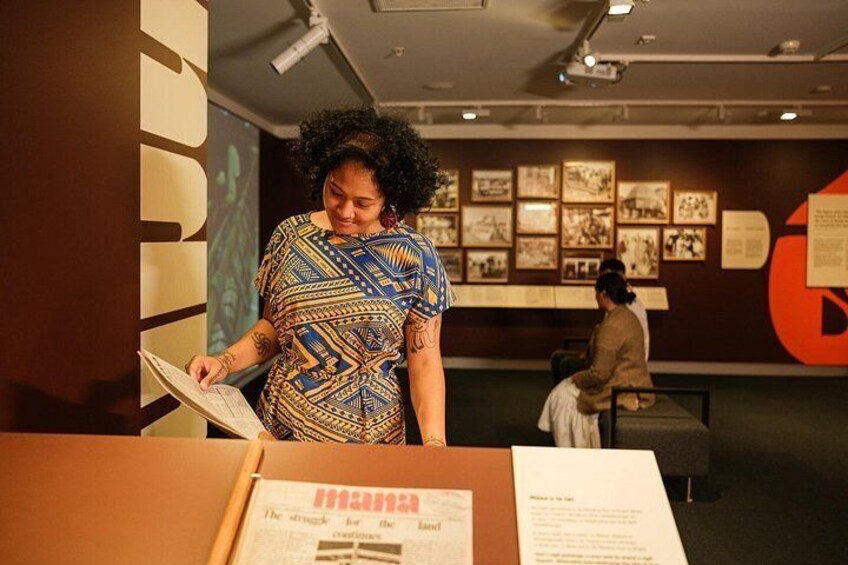 A person reading a book in an indoor exhibition space with informational displays and a large red circular design on the wall. 5