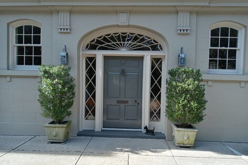 A building with a grey door, two potted plants, and a cat on the steps. 5