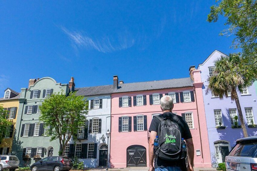 A man walking on a street with colorful buildings. 3
