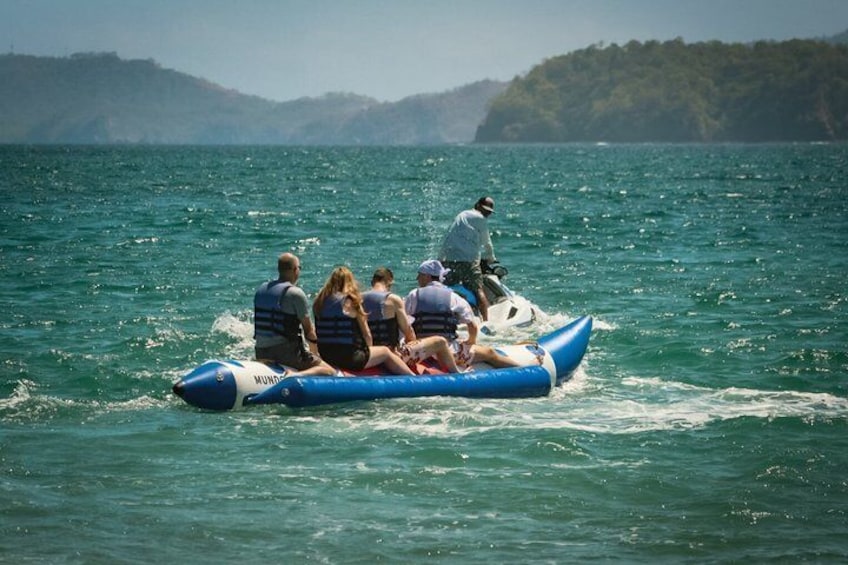 Un grupo de personas en un bote inflable azul sobre una masa de agua, con colinas al fondo. 1