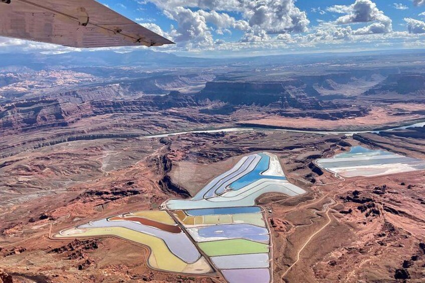 Un vaste paysage de canyon, parsemé de dépôts minéraux aux couleurs vives, et traversé par une route sinueuse. 2