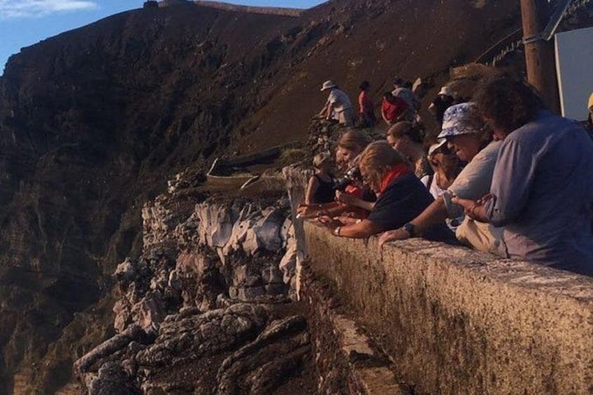 A group of people sitting on a stone ledge overlooking a steep cliff. 5