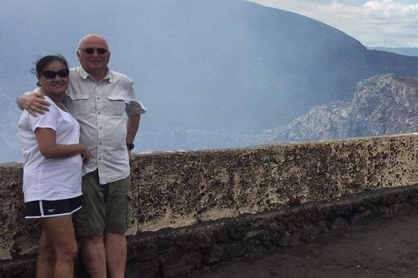 Two people standing on a concrete ledge with a mountainous landscape in the background. 3