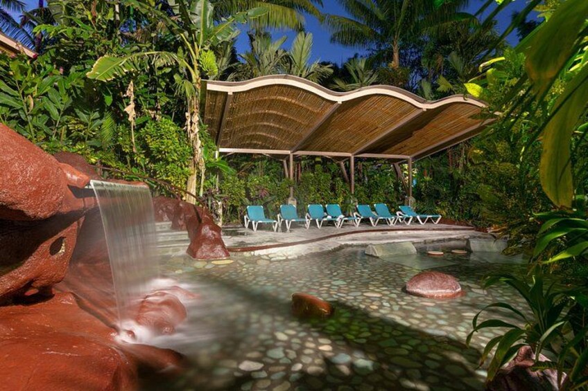 Un complexe hôtelier tropical doté d’une cascade, de chaises longues et d’une végétation luxuriante. 2