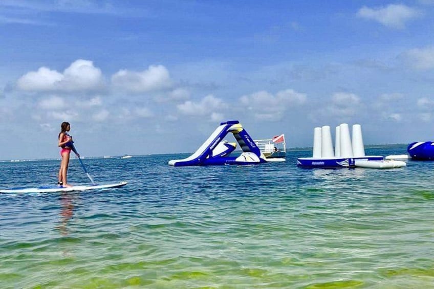 En person paddleboarder, oppustelige vandrutsjebaner og et roligt hav. 1