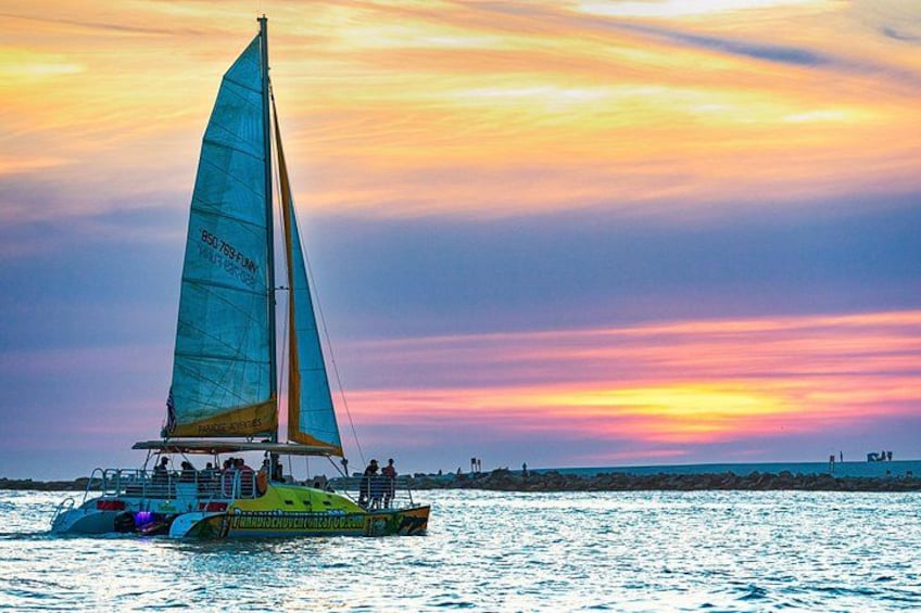 A sailboat with a blue sail on a body of water during sunset. 1
