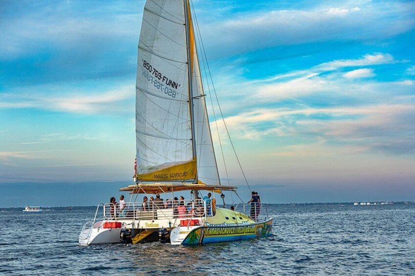 A sailboat with passengers on a calm sea, a clear sky, and distant land. 5
