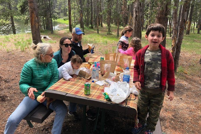 A group of people sitting at a picnic table in a wooded area. 5