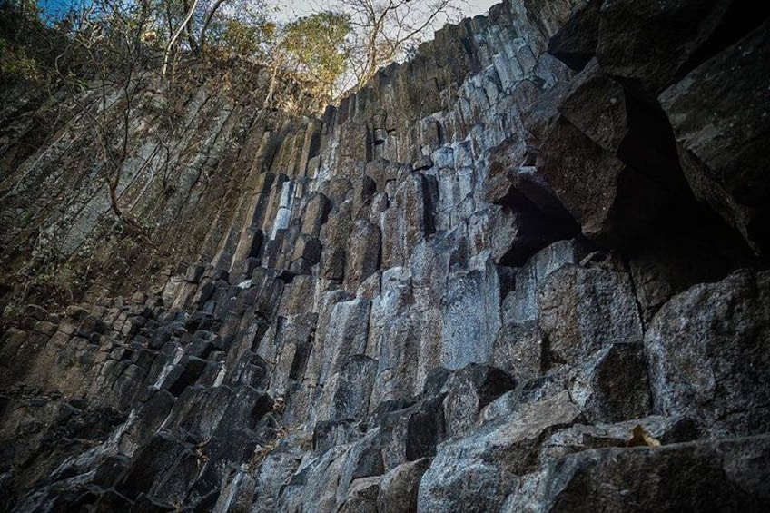 A rocky cliff with layered rock formations and sparse vegetation. 5