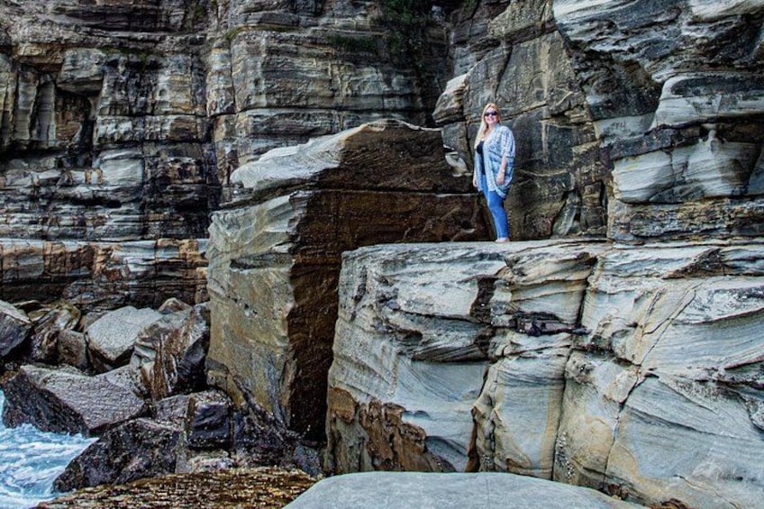 A person standing on a rocky cliff by the sea. 2