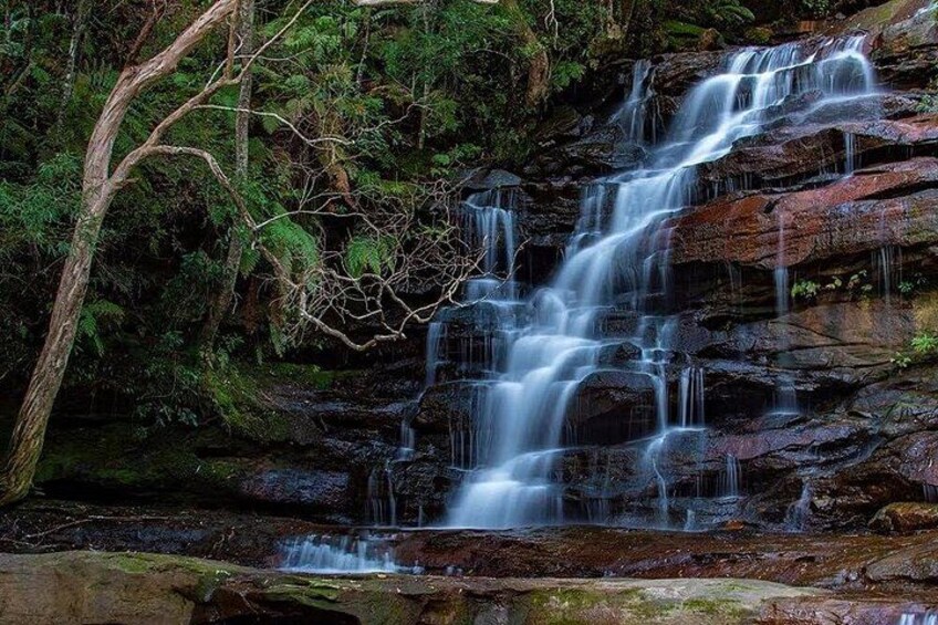 A multi-tiered waterfall surrounded by dense forest. 2