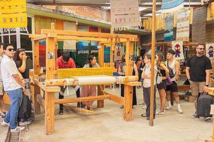 A weaving workshop with people observing and participating in the process. 4