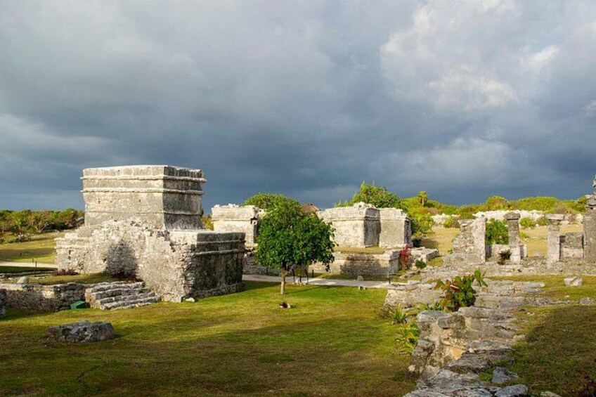 Ancient stone ruins with a tree in the foreground and a cloudy sky. 1