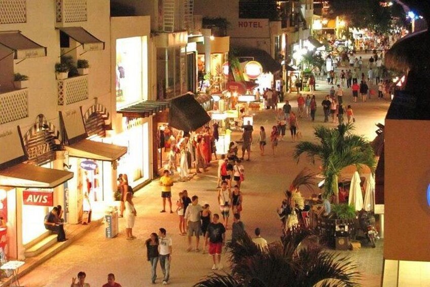A busy street at night with people walking, shops, and a hotel. 5
