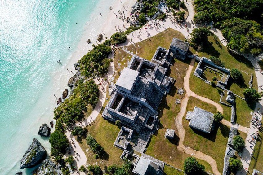 An aerial view of a coastal archaeological site with ruins, a beach, and a pathway. 1