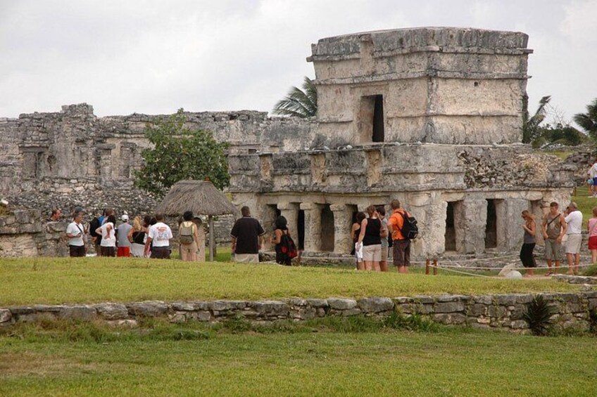 A historical stone structure with tourists observing. 2