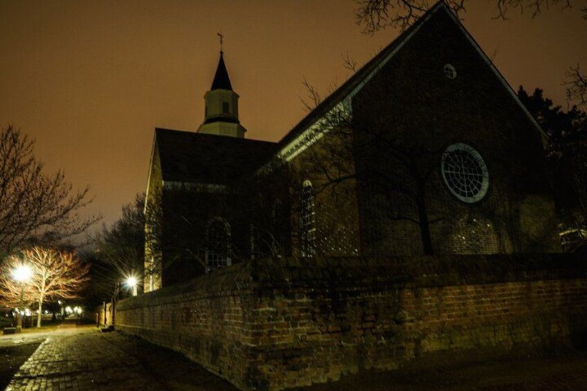 En kyrka byggd av tegel, med ett torn och ett runt fönster, fotograferad under natten. 4