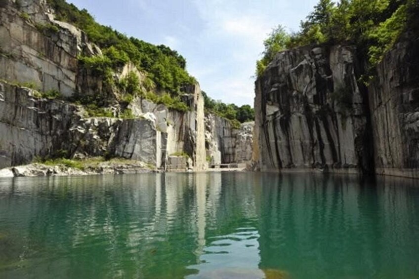 A natural landscape with a body of water, rocky cliffs, and greenery. 1