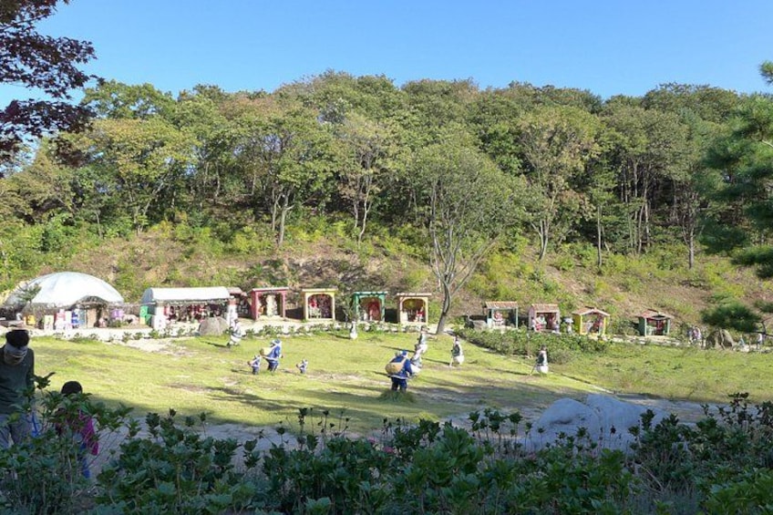 A park with green grass, trees, and several small structures. 3