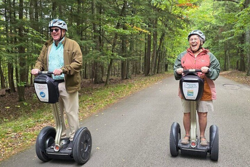 Two people riding Segways on a forested path. 4