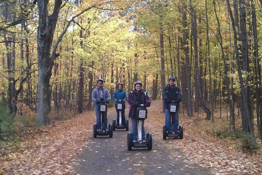 Eine Gruppe von Personen fährt auf Segways durch einen bewaldeten Bereich. 2