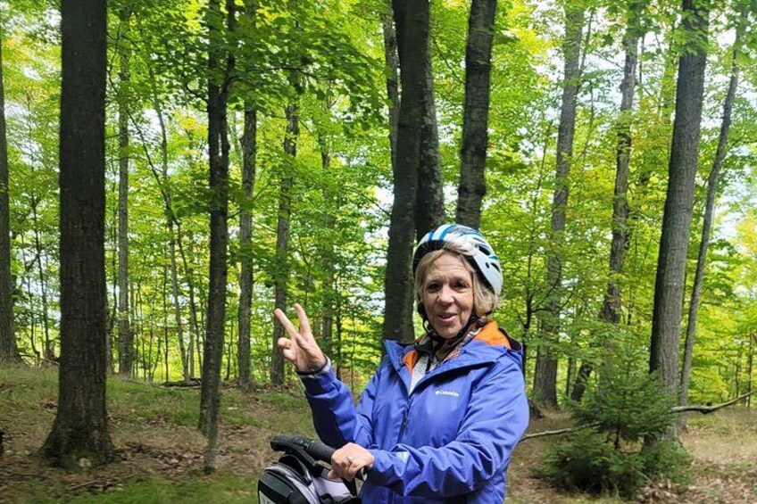 A person in a forest with trees and a backpack. 3