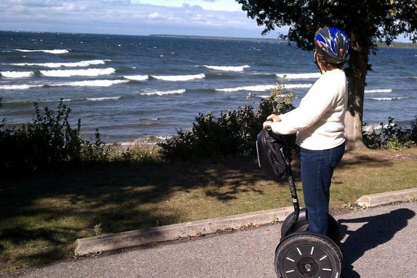 A person on a Segway near the ocean, holding a bag, with waves in the background. 2