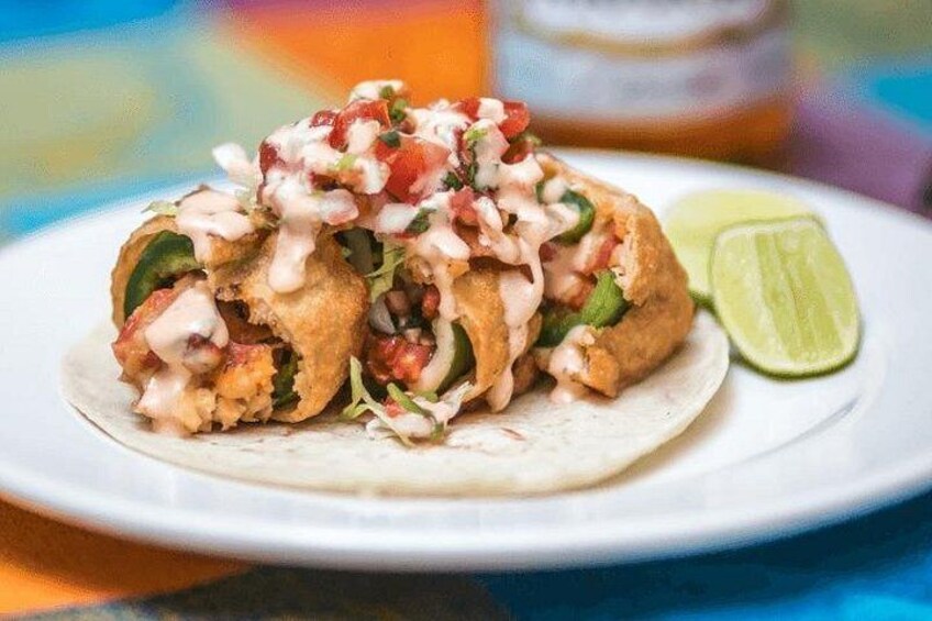 En tallerken med to tacos, et limebåd og et glas i baggrunden. 1