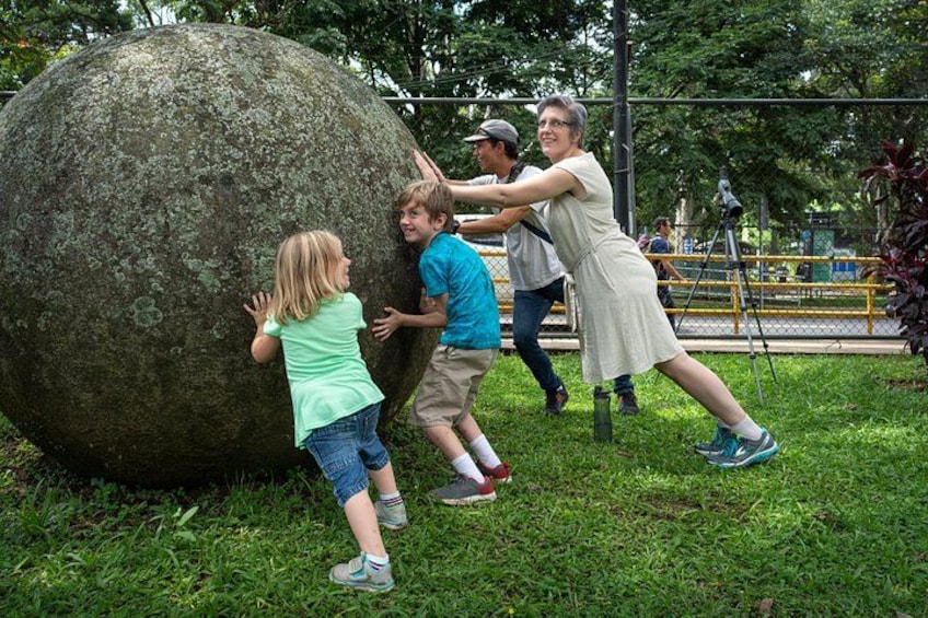 People playing with a large stone ball in a park. 4