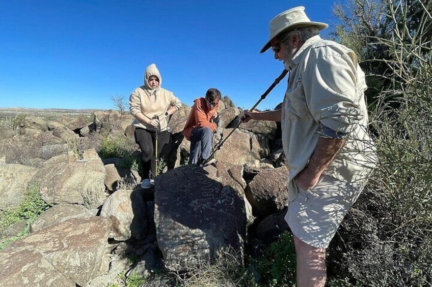 Trois personnes font de la randonnée dans un terrain rocheux, sous un ciel bleu dégagé. 4