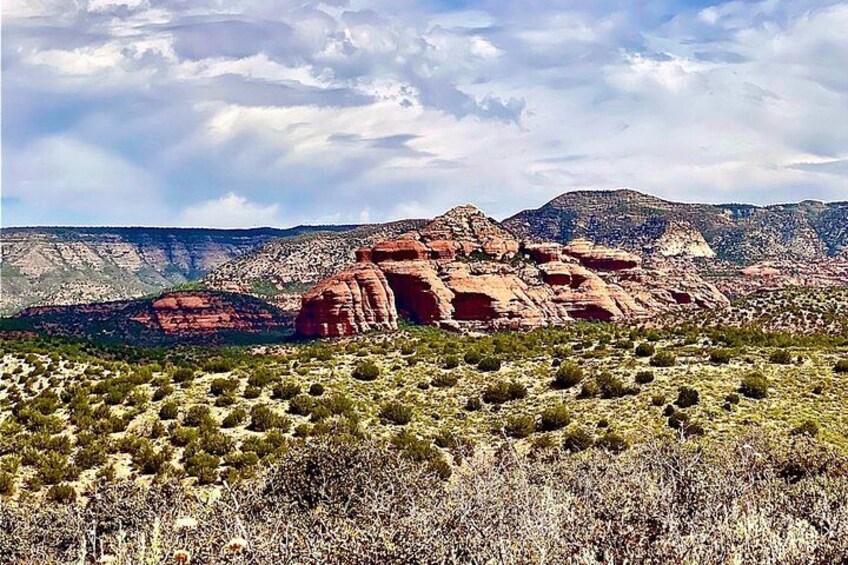 A desert landscape with red rock formations and sparse vegetation. 2