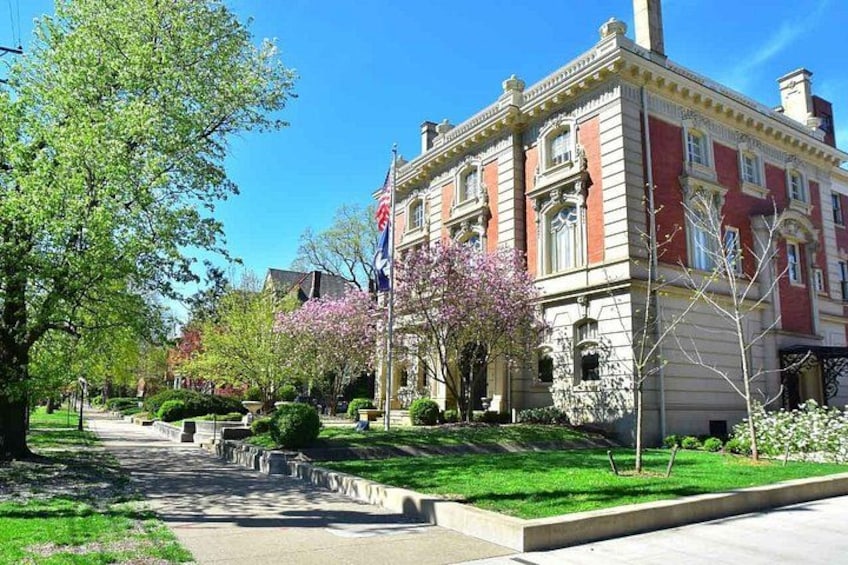 A red brick building with a flag, surrounded by green grass and trees. 4
