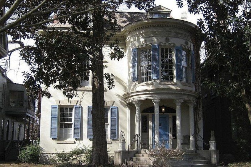 A classical building with a curved facade, large windows with shutters, and a central entrance with steps. 3