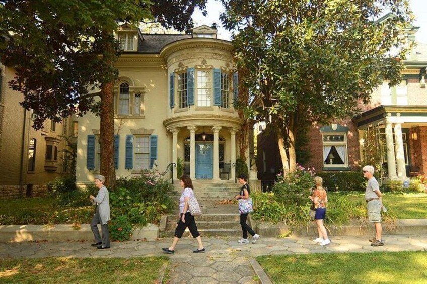 A historic house with a curved facade, blue shutters, and a well-maintained garden. 5