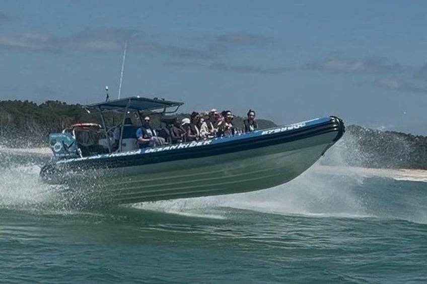 Een speedboot met passagiers vaart door het water, waarbij een kielzog ontstaat. 1
