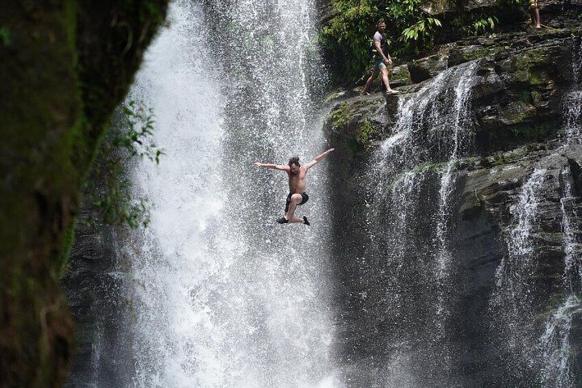 A person jumping off a cliff into a waterfall. 1