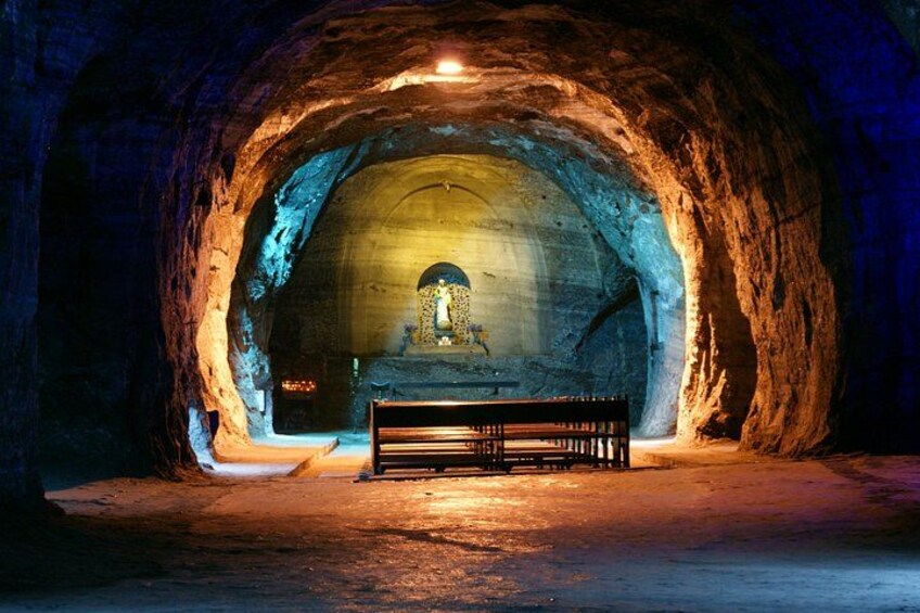 Una cueva con un banco y una estatua en el centro. 3