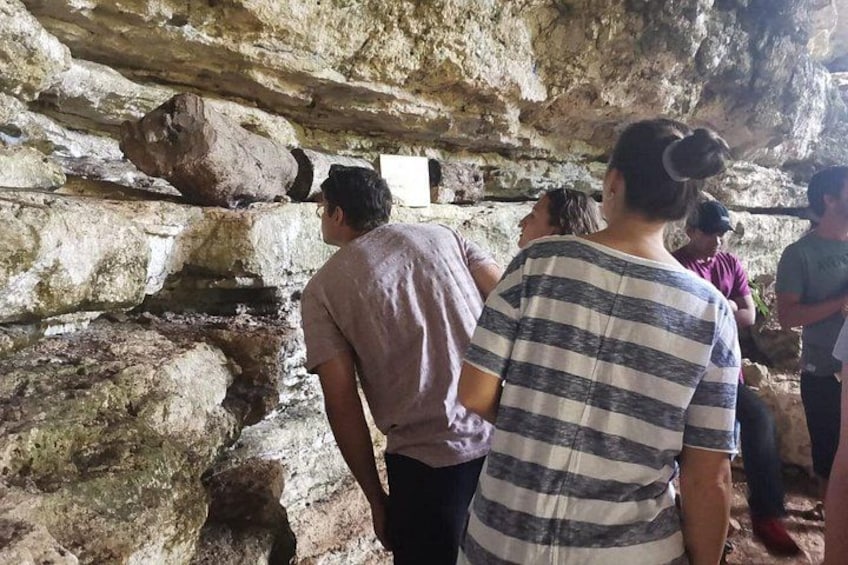 A group of people inside a cave with rocky walls and a small opening. 3